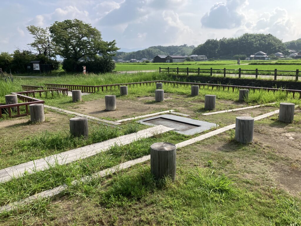 飛鳥水落遺跡の基壇と柱位置表示を周囲の田園とともに見渡した写真